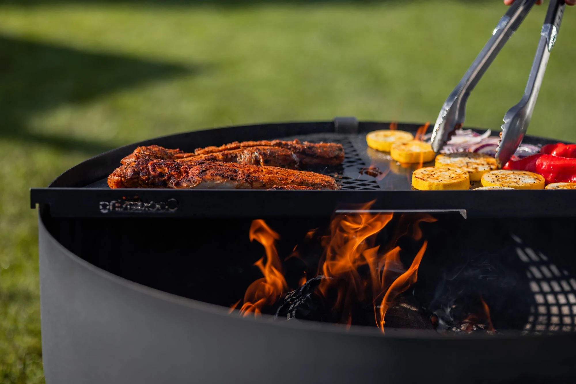 Meat and vegetables grilling on a COOK KING grate over open flames